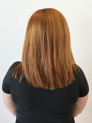 Vorher Foto: Rückansicht einer Frau mit mittellangem, unebenem hellbraunem Haar mit einem herausgewachsenen Ansatz vor dem Färben.
