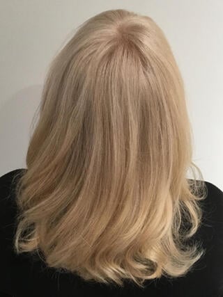 Nachher-Foto: Rückansicht einer Frau mit mittellangen, gleichmäßig blonden Haaren nach dem Färben.