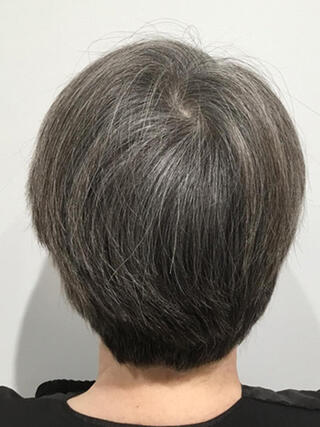 Vorher Foto: Rückansicht einer Frau mit kurzen schwarzen Haaren mit vielen grauen Haaren vor dem Färben.