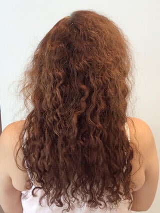 Vorher Foto: Rückansicht einer Frau mit langen, strapazierten roten Haaren vor dem Färben.