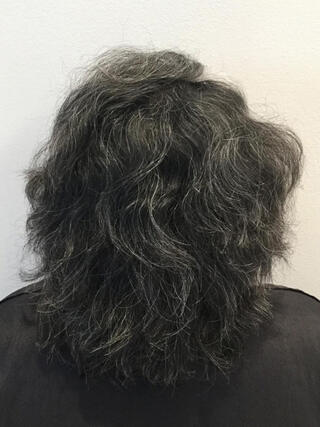 Vorher Foto: Rückansicht einer Frau mit kurzen schwarzen Haaren mit vielen grauen Haaren vor dem Färben.